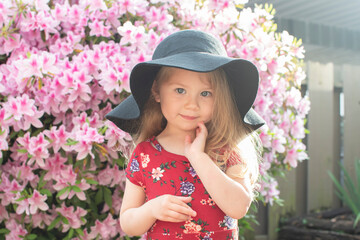 Smiling cute caucasian blonde toddler girl in a hat enjoying summer sunny day outdoors	
