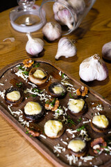 Fototapeta na wymiar Roasted portobello mushrooms stuffed with cheese and herbs on a black iron background, top view. Vegetarian meal