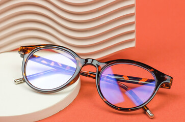 Leopard glasses on a colored background. Stylish glasses on a podium made of natural stone