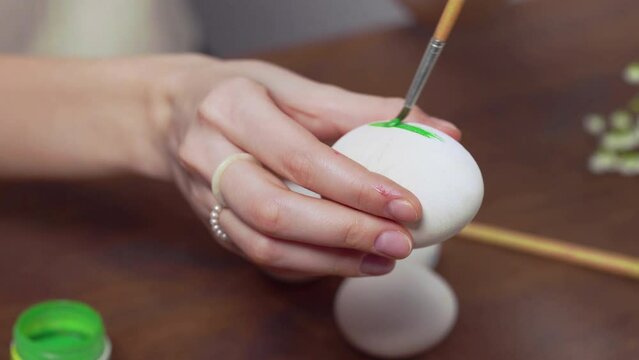 Close-up of a woman's hands painting an easter egg with a paintbrush. Church holiday-Easter
