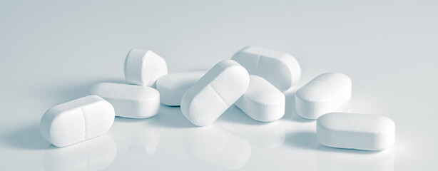 Medical background of many capsule tablets or pills on white table. Close up. Healthcare pharmacy...