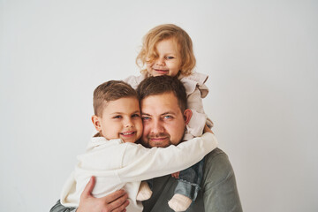 Close-up portrait of father, son and daughter. Happy family hugging and smiling on white background. Paternity. Single father bring up his children.