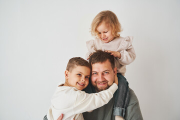 Close-up portrait of father, son and daughter. Happy family hugging and smiling on white background. Paternity. Single father bring up his children.