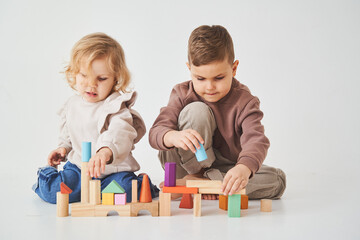 Little kids brother and sister smiling, having fun and playing colored bricks toy on white background. Children have smiling and have fun together.