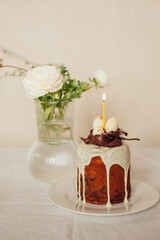 Holy Easter.
The original Easter cake will be decorated with a chocolate nest and eggs. Easter cake is on the table, also on the table is a vase of flowers. The holiday table.