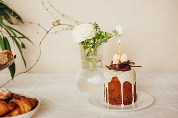 Holy Easter.
The original Easter cake will be decorated with a chocolate nest and eggs. Easter cake is on the table, also on the table is a vase of flowers. The holiday table.