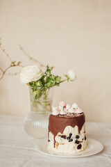 Easter cake decorated with chocolate and marshmallows. Easter cake is on the table, also on the table is a vase of flowers. The holiday table.