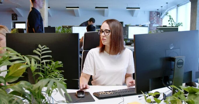Busy Caucasian woman sitting at computer screen and typing on keyboard. Customer support online. Female employee working at office and texting. IT worker. Workday at coworking center. - Powered by Adobe