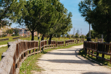 Urban park with dirt road and wooden fences with buildings in the background. Copy space. Selective focus.