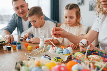 Fototapeta premium Sitting by the table. Happy family celebrating Easter holidays together