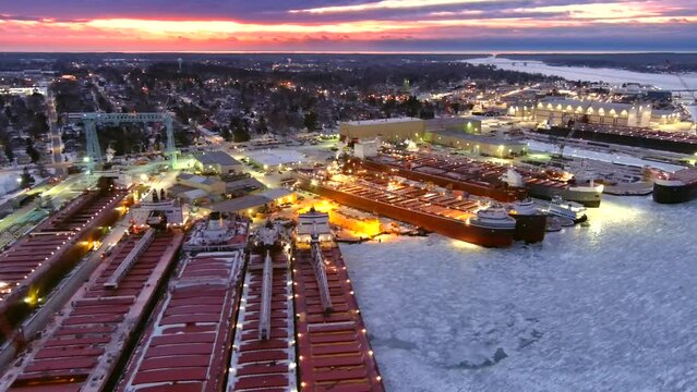 Giant Great Lakes freighter ships being built, refurbished, repaired, in winter shipyard, icy cold waters, twilight aerial view.