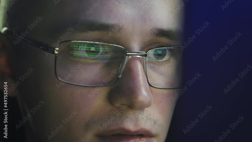 Wall mural the programmer in glasses looks at the monitor screen. he's engrossed. close-up of his face. the gla