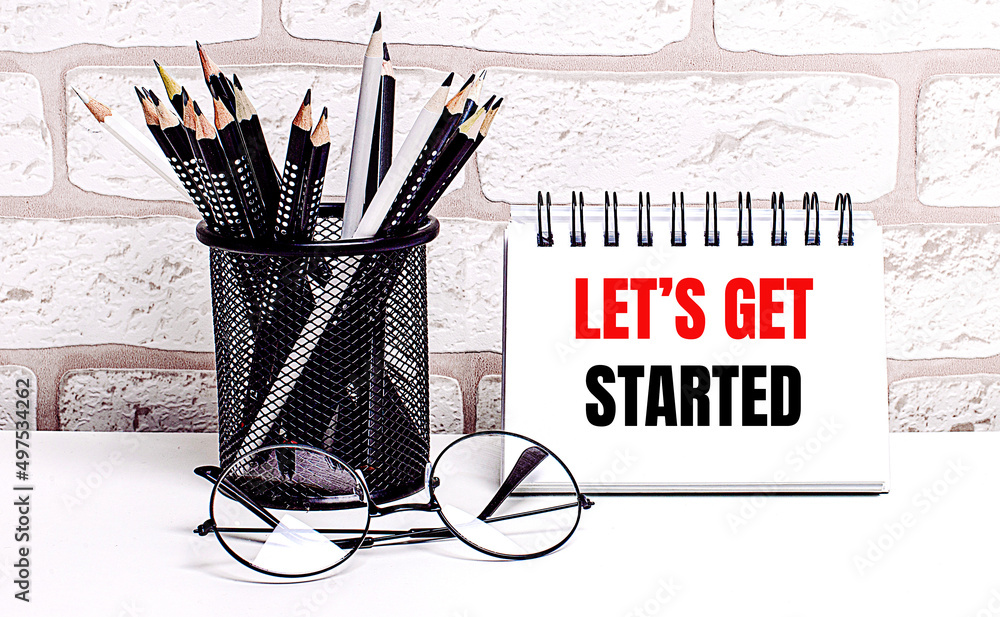 Poster a workplace in the house with glasses, pencils in a stand and a notebook with text let is get starte