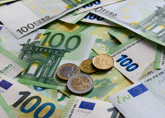 Euro cent coins on the background of 100 Euro banknotes arranged in random order