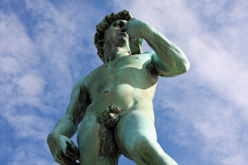 Low angle closeup of David of Michelangelo in Piazzale on blue cloudy sky background