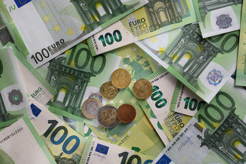 Euro cent coins on the background of 100 Euro banknotes