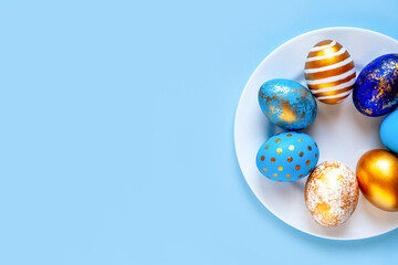 easter eggs blue gold color beautiful painted for holy easter lie on a plate on a blue background