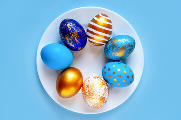 easter eggs blue gold color beautiful painted for holy easter lie on a plate on a blue background