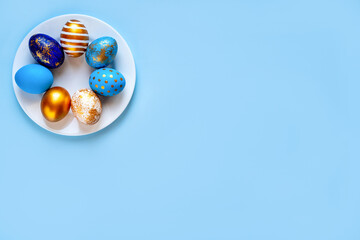 easter eggs blue gold color beautiful painted for holy easter lie on a plate on a blue background