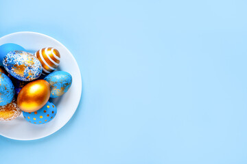 easter eggs blue gold color beautiful painted for holy easter lie on a plate on a blue background