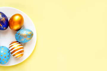 easter eggs blue gold color beautiful painted for holy easter lie on a plate on a yellow background