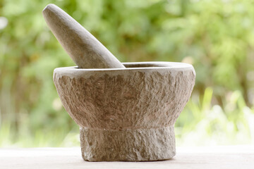 Closeup of a pestle and mortar made of stone on a blurred background - obrazy, fototapety, plakaty