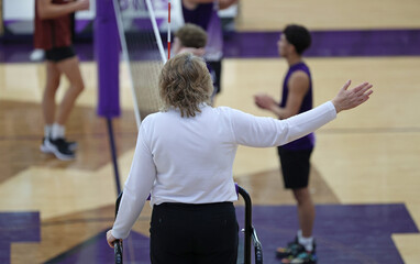 A volleyball official signals side out.