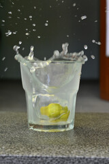 closeup the lemon juice flow in the glass over out of focus grey brown background.