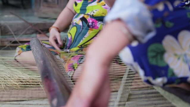 Two women handworking on sedge mat weaving Vietnamese traditional craft. Close up