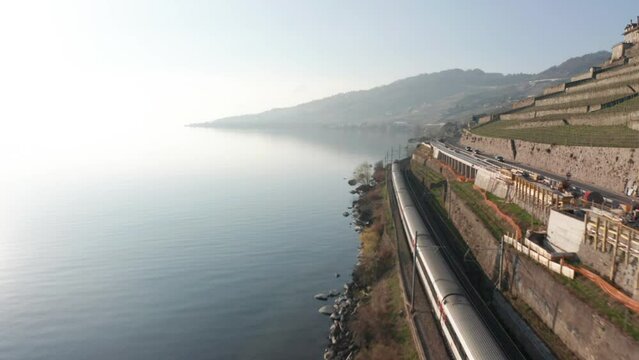 Drone following train driving next to beautiful lake