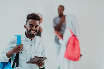 University lifestyle handsome young African student man holding a tablet computer and smiling while standing against university with his friends have a team meeting in the background. High-quality