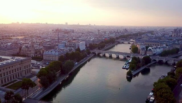 Descending drone flying over Seine river in Paris towards Ile de la Cite and La Samaritaine in reconstruction. Romantic view on city at sunrise.