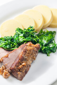 pork meat with garlic served with spinach and potato dumplings