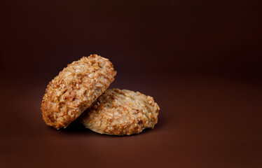 Handmade oatmeal cookies on a brown background.