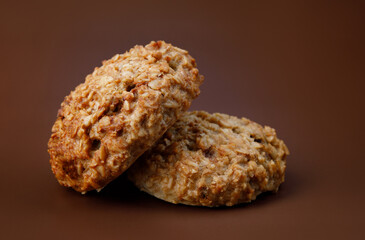 Handmade oatmeal cookies on a brown background.