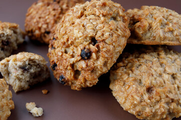 Whole and crushed handmade oatmeal cookies on a brown background. View from above .