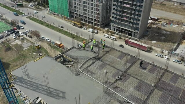 Aerial Drone Shot of Construction Workers Pouring Concrete on on top of High Building
