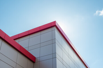 The exterior wall of a contemporary commercial style building with aluminum metal composite panels and glass windows. The futuristic building has engineered diagonal cladding steel frame panels.