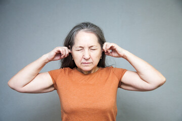 Emotional middle-aged woman on   gray background.