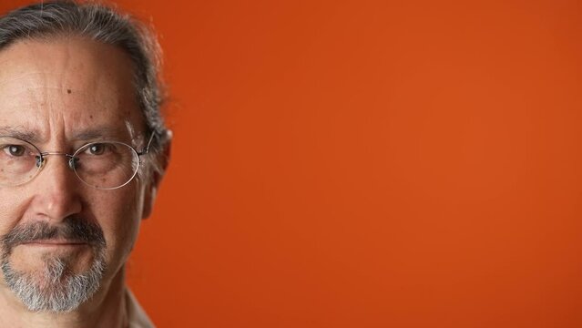 Half face closeup portrait of happy smiling senior man 50s 60s isolated on plain solid orange background studio.