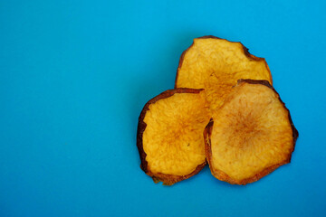 three dried peach chips lie on a blue background. healthy homemade food. top view
