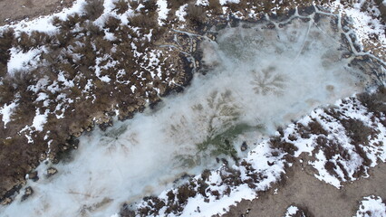 Dark patterns on the melting ice surface on the lake in spring