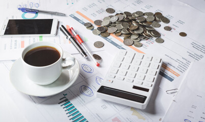 A cup of black coffee on an investor's desk with a financial report