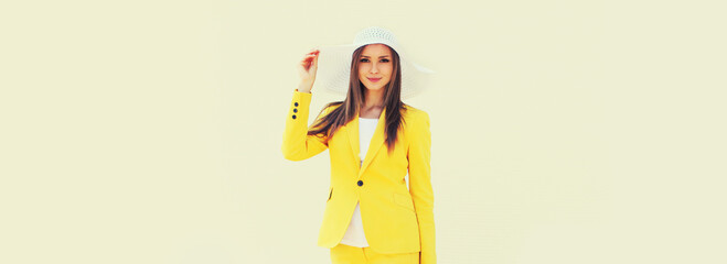 Portrait of beautiful young woman wearing white straw hat and yellow suit in the city