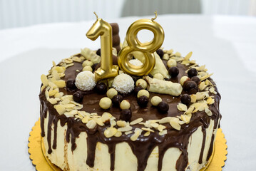 Festive cake with golden candles for eighteenth birthday or anniversary celebration on white table