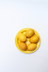Yellow Easter eggs on a yellow plate and on a white background, copy space
