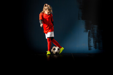 The girl football player is having fun with the ball indoors