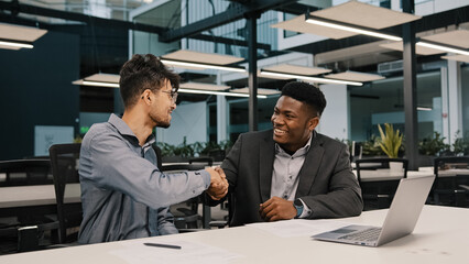 Two diverse men arabian african colleagues co-workers cooperate discuss online project at workplace businessmen finish talk shaking hands corporate teamwork at office meeting synergy working together