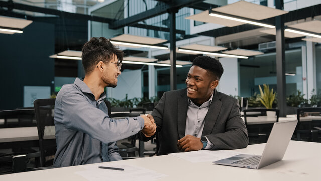 Two Diverse Men Arabian African Colleagues Co-workers Cooperate Discuss Online Project At Workplace Businessmen Finish Talk Shaking Hands Corporate Teamwork At Office Meeting Synergy Working Together