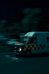 Vertical shot of an ambulance driving fast on a road at night © Rohan Kamble/Wirestock Creators